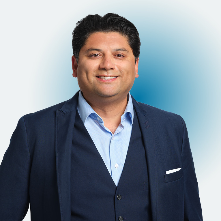 Cropped close up portrait of Jason D'Mello smiling, in a dark blue suit on a white background