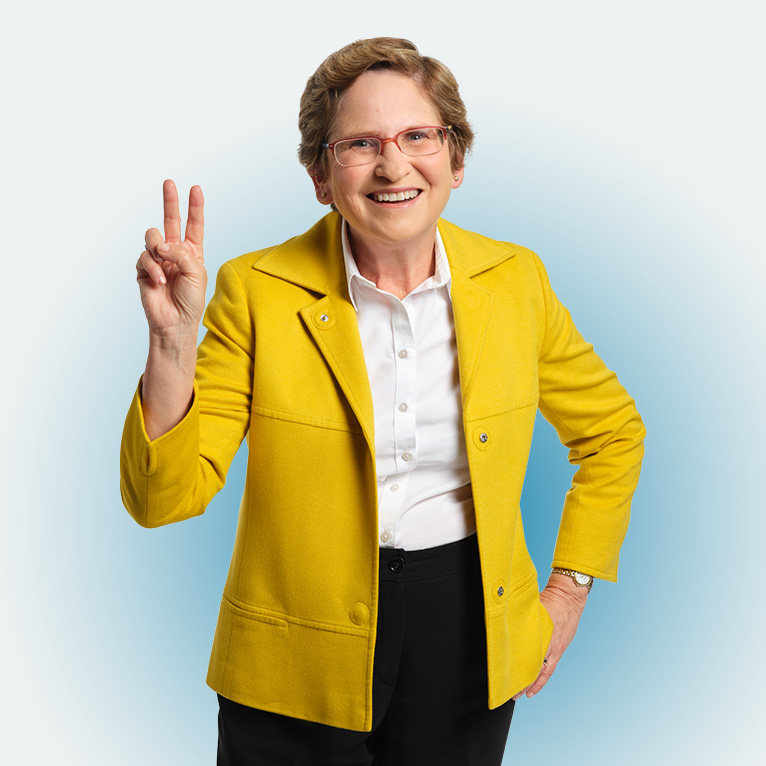 Cropped photo of LMU Law School professor Laurie Levenson smiling at the camera with her right hand held in a peace sign, her other hand on her hip, on a white background.